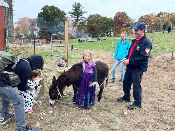 Children and families interacting with Bessie the donkey on the farm